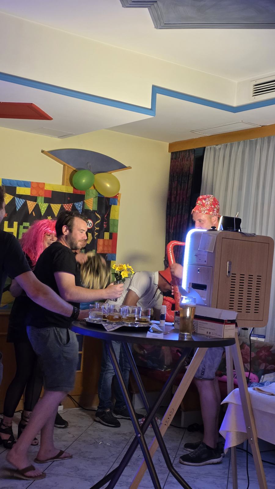Partygäste mit Accessoires an der Fotobox bei einer Geburtstagsfeier